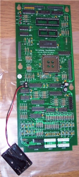 A green board with wires and buttons on it
