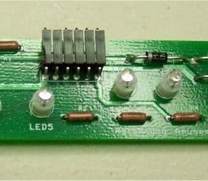 A green circuit board with many lights on it.