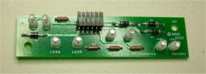 A green circuit board with many lights on it.